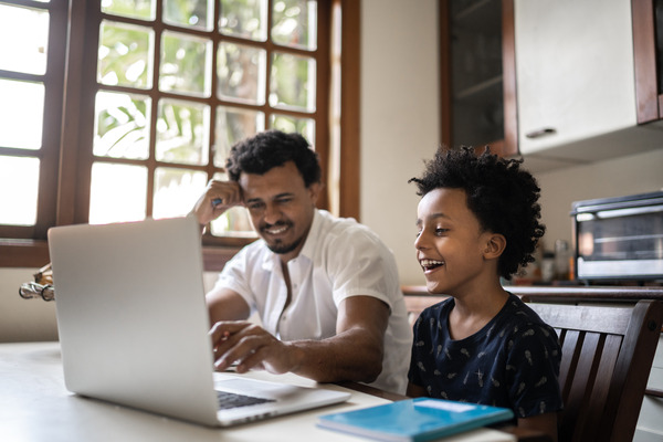 Parent helping their child use a laptop