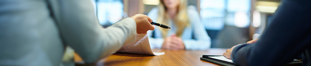A woman hands a pen to another woman across a table