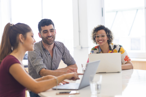 Three people smiling and looking at a laptop
