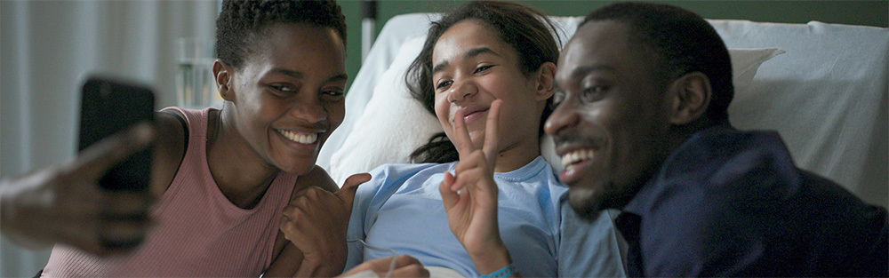 Parents take a selfie with their smiling daughter in a hospital