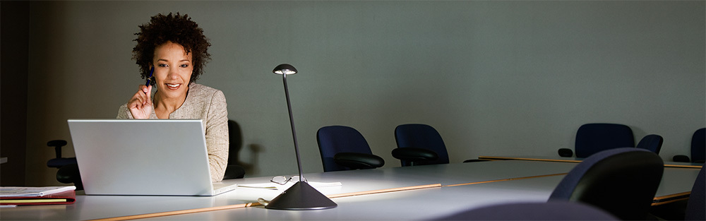 A woman uses a laptop in a darkened conference room.