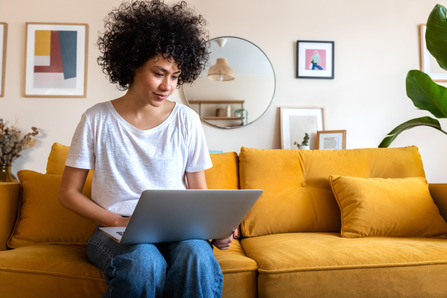 Woman sitting on couch using laptop