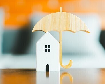 small wooden toy house with small wooden umbrella covering it