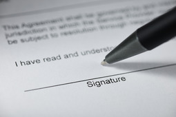 Signature line on a document with a pen ready to sign
