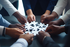 Zoomed in image of a team with their hands in holding puzzle pieces to fit them together.