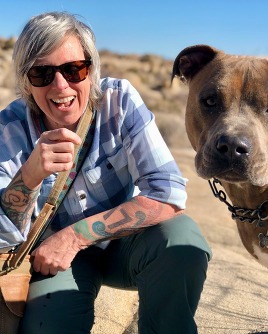 A picture of Karen Capalidi kneeling on one knee with her dog.