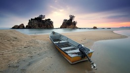 An image of a small motorboat on a sandbar in a tropical area. 