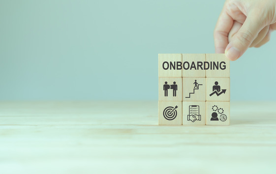 A hand moving around wooden blocks, one of which has the word onboarding written on it.