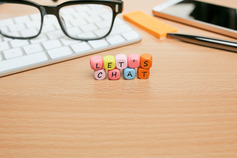Image with reading glasses and wood block with the words let's chat placed on a desk