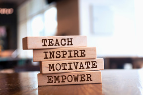 Wooden blocks stacked with the words: Teach, Inspire, Motivate, Empower—representing leadership and development.