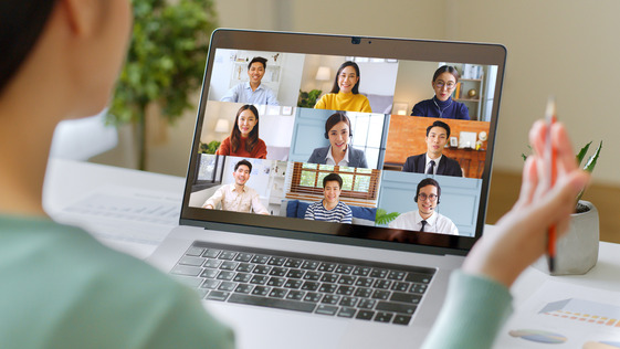 Person attending a virtual meeting on a laptop displaying a nine person video conference grid.