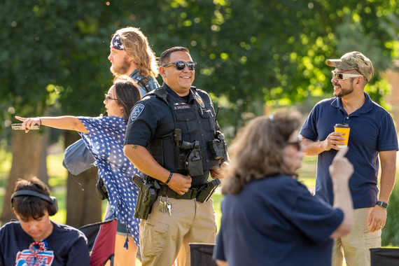 A University of Northern Colorado police officer smiles while chatting with a resident in a crowd at a Greeley parade