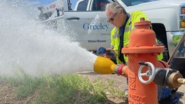 City worker measures flow of water coming from fire hydrant.