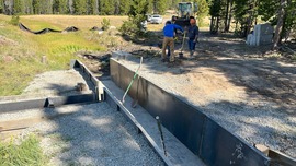 Crew members work on installing a steel flume along a creek.