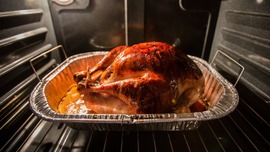 A turkey sits in a baking dish inside an oven.