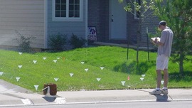 Man records data while performing an irrigation assessment of a front yard.