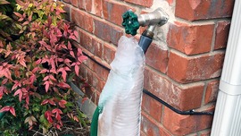 A spigot with an attached garden hose is encased in ice.