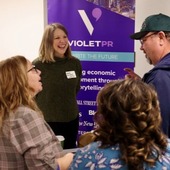 Vendor Meet and Greet Event. Woman stands behind a table and chats with three city employees about her company's services.