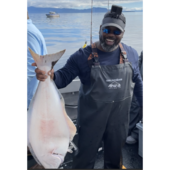 Robert Thompon on a boat wearing fishing waders and holding a very large fish.