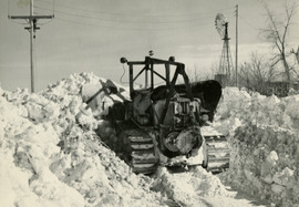 old photo of heavy equipment working to move snowdrifts that measured as much as 15 feet tall