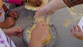 hands grinding corn on stone 
