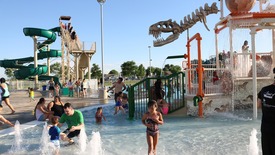 Families play at Discovery Bay Waterpark zero depth area and slide