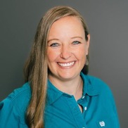 Juli Wacker against a dark grey background wearing a bright turquoise shirt