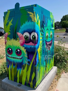 city utility cabinet wrapped in bright colored art that depicts friendly monsters
