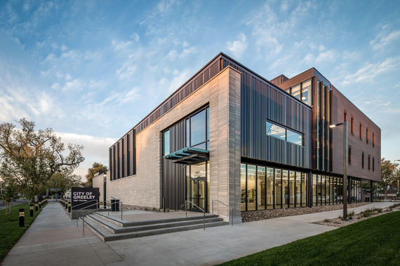Exterior of City Center South building, east entrance. Building is two stories with stone walls and floor to ceiling glass windows.