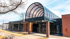 Exterior of the former Atmos building with brick walls and a glass arch over the entrance.
