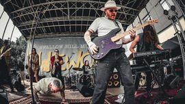Fisheye view of band onstage with guitar, keyboard, and saxophones.