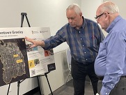 two men look at a poster board with details about the project.