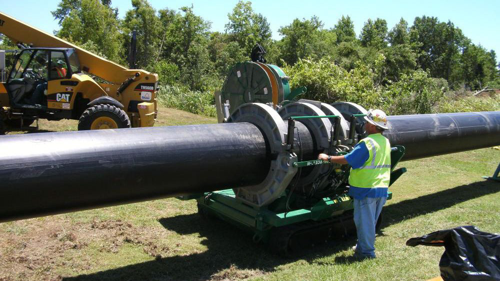 a person stands next to a large pipe that is being put in place.