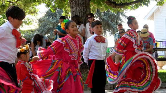 children wearing colorful clothing dance outside.
