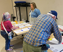 a person writes on a poster board while two others talk to each other