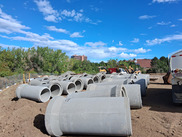 Large sewer pipes on the ground in a dirt lot
