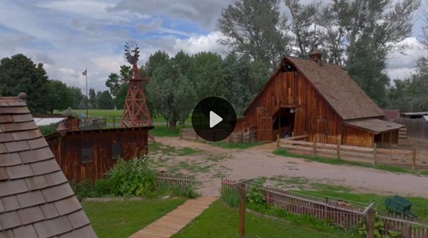 Large wooden barn at the Littleton Museum overlaid with play button icon