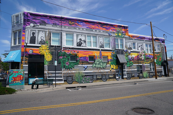 Mural in downtown Littleton, covering a two-story building with a streetcar featuring black-and-white portraits, large flowers