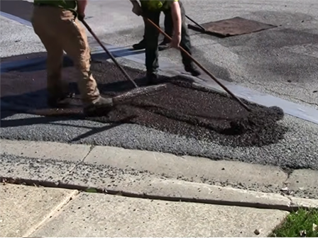 Close-up of paving crew spreading asphalt