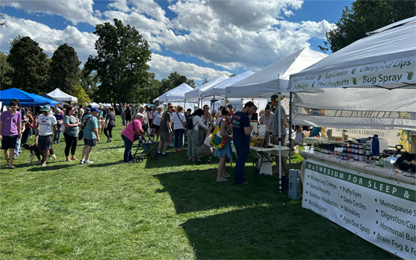 Large crowd at an outdoor craft fair with several vendor tents