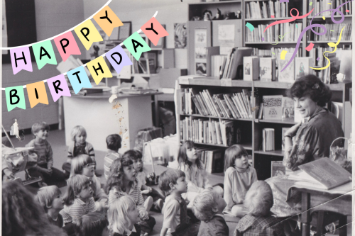 A black and white photograph of a librarian reading to a group of young schoolchildren. Text reads, Happy Birthday