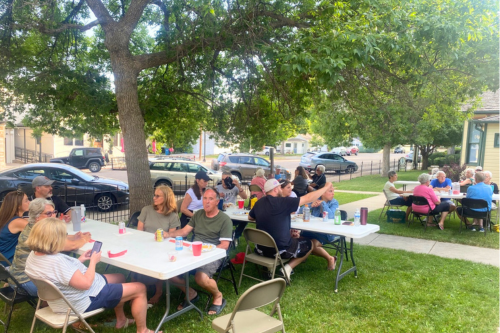 A large group eats outdoors at picnic tables