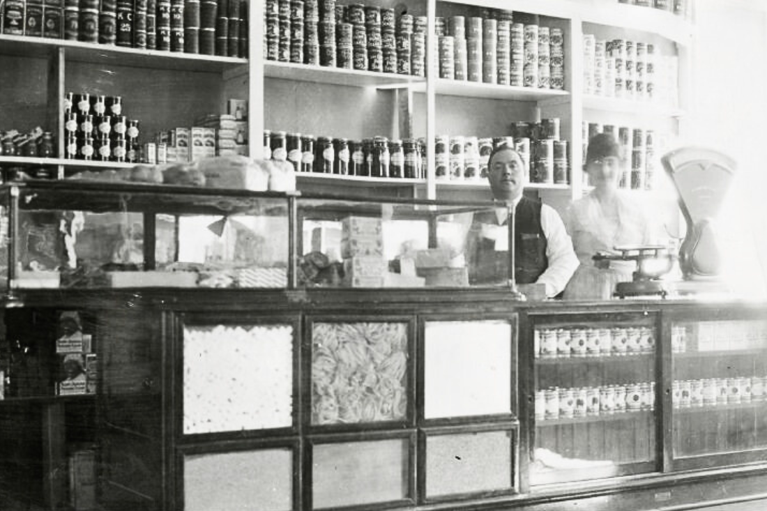 black and white photo of man and woman behind counter at grocery store