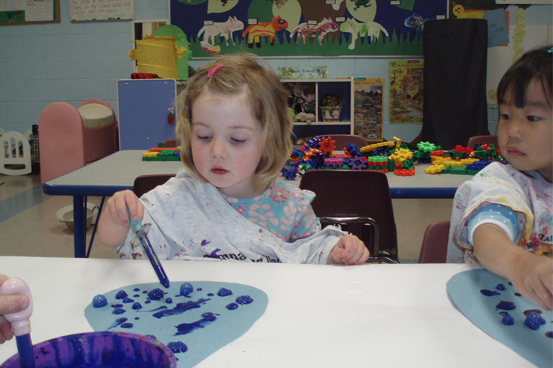 young girl painting with blue paint