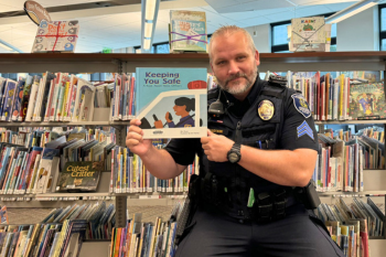 Police Officer Storytime: image of officer in front of rows of books, holding up a picture book