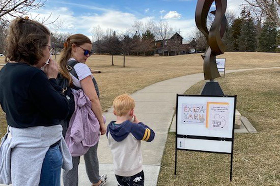 two adults and child reading a sign