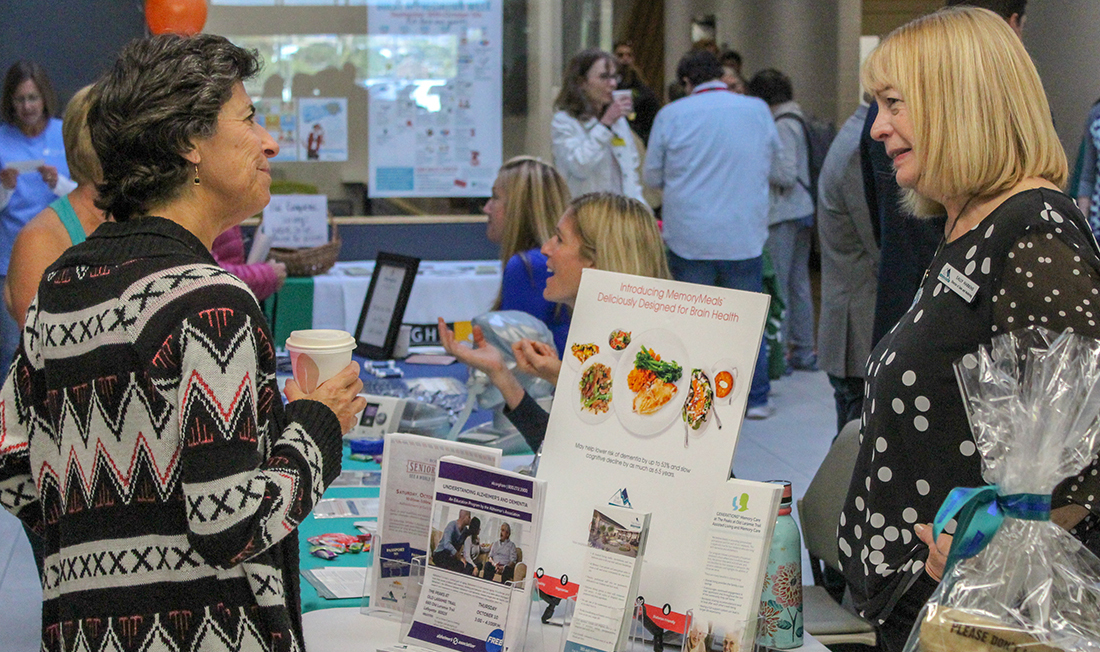 senior talking to booth representative at a wellness fair