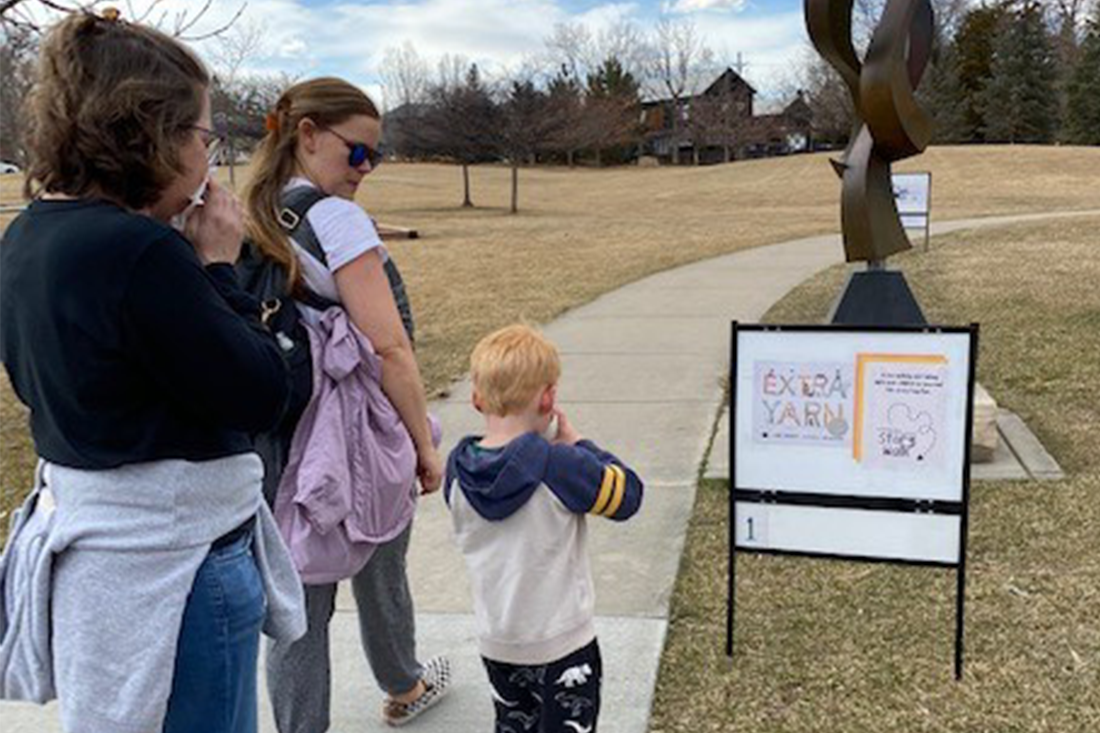 children walking out side and reading a book posted on a sign