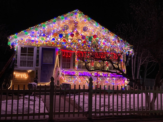Photo of a small white house covered in Christmas lights and decorations