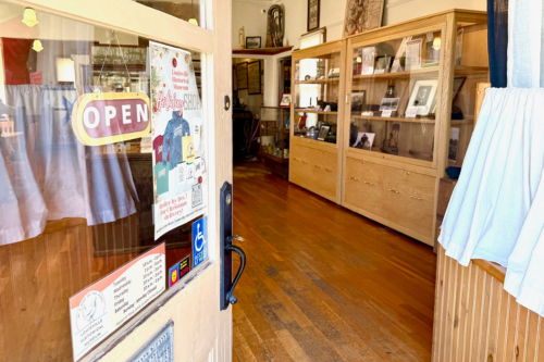 Door with open sign opens up to interior of museum with display cases visible
